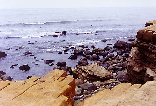 Layers of broken rock above the beach result from erosion of waves below.